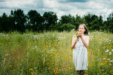 Mädchen pflückt wilde Blumen in einem Feld in Süd-Michigan - CAVF79530