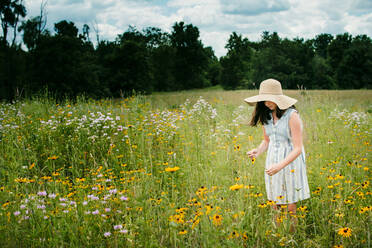 Girl Wearing a Floppy Sun Hat Picking Flowers in Southern Michigan - CAVF79531