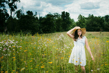 Teenager-Mädchen geht durch ein Wildblumenfeld in Süd-Michigan - CAVF79532