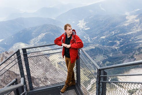 Millennial-Mann genießt Bergblick auf die Alpen von der Aussichtsplattform - CAVF79540