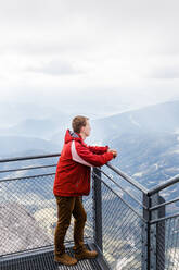 Millennial guy enjoys mountain views of Alps from observation deck - CAVF79541