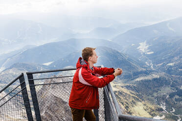 Millennial-Mann genießt Bergblick auf die Alpen von der Aussichtsplattform - CAVF79543