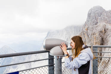 Junge Frauen betrachten die Berge mit einem Fernglas von einem Aussichtspunkt aus - CAVF79549