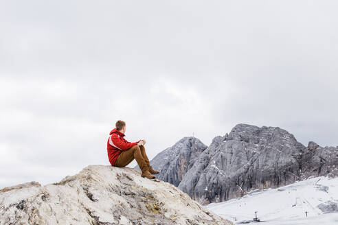 Ein junger Mann aus der Jahrtausendwende genießt die Aussicht auf die Alpen auf einem Gletscher - CAVF79555