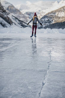 Junge Frau beim Schlittschuhlaufen auf dem gefrorenen See in Richtung Eisspalt - CAVF79574