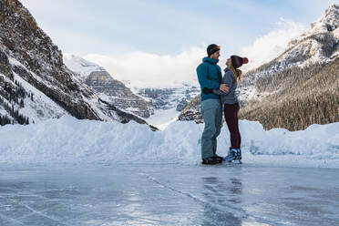 Junges Paar beim Schlittschuhlaufen auf dem gefrorenen Lake Louise im Winter - CAVF79576