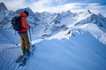 Skifahrer in orangefarbener Jacke auf einem Bergkamm - CAVF79679