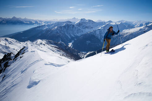 Mann in blauer Jacke beim Skitourengehen auf dem Grat - CAVF79681