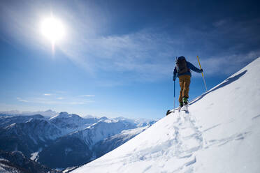 Ski touring uphill with a mountain backdrop - CAVF79684
