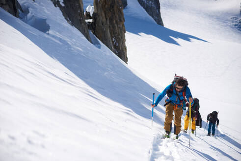 Group of 3 people ski touring up hill - CAVF79692