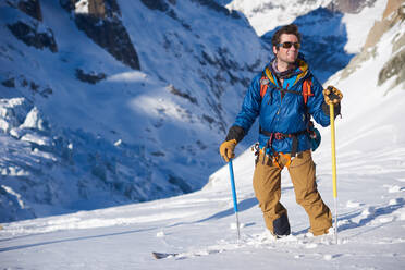 Lächelnder Skifahrer in blauer Jacke stand still auf einer Gletscherabfahrt - CAVF79693