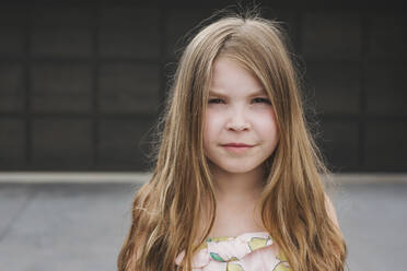 Closeup of a young girl standing in front of garage door - CAVF79698