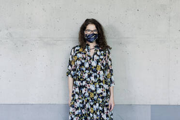 Woman wearing homemade mask in front of a wall - FLLF00450