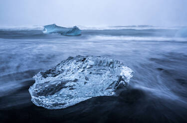 Iceland, Ice chunk lying on black sand of Diamond Beach - DAMF00413