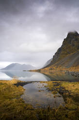 Island, Wolken über ruhigem Seeufer mit Bergen im Hintergrund - DAMF00417
