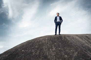 Mature businessman standing on top of a disused mine tip - JOSEF00357