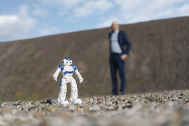 Miniaturroboter und Geschäftsmann auf einer stillgelegten Bergwerkshalde - JOSEF00414
