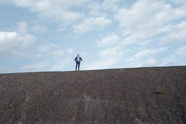 Mature businessman standing on a disused mine tip - JOSEF00421