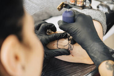 Female tattooist tattooing on a woman's arm - JSMF01541