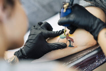 Female tattooist tattooing on a woman's arm - JSMF01543