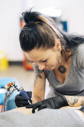 Female tattooist tattooing on a woman's arm - JSMF01545