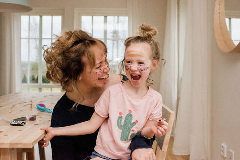 Mutter und Tochter lachen beim Spielen mit Make-up zu Hause - CAVF79935