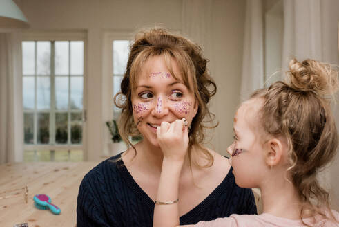 Mutter und Tochter spielen mit Make-up und Verkleidung zu Hause - CAVF79938