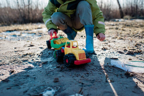 Kleiner Junge spielt allein mit Lastwagen am Strand - CAVF79940