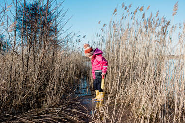 Young girl playing in long grass by the beach in winter - CAVF79942
