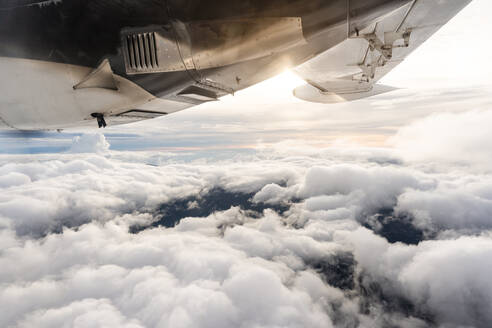 Blick auf den Sonnenuntergang über den Wolken aus dem Flugzeugfenster - CAVF79995