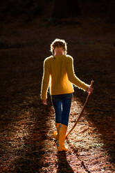 Tween girl with walking stick in forest with beautiful light - CAVF80010