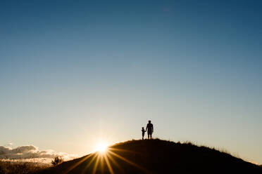 Silhouette von Vater und Sohn auf dem Gipfel eines Hügels bei Sonnenuntergang - CAVF80013