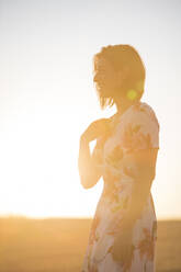 Woman observing the dry field at sunset - CAVF80039