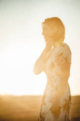 Woman observing the dry field at sunset - CAVF80040