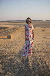 Frau, die das trockene Feld bei Sonnenuntergang beobachtet - CAVF80041