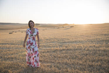 Frau, die das trockene Feld bei Sonnenuntergang beobachtet - CAVF80042