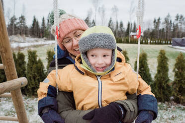 Mutter und Sohn lachen und haben Spaß beim Spielen draußen im Schnee - CAVF80059