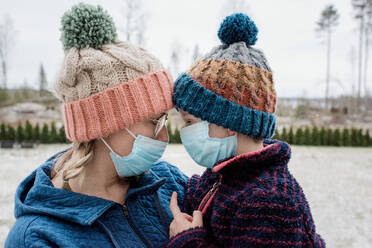 Mother and son looking at each other with face masks for protection - CAVF80062