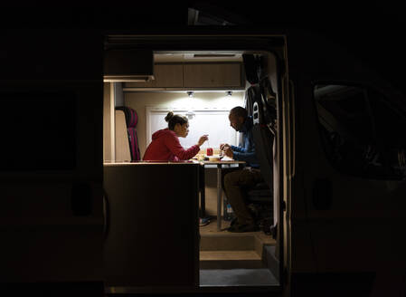 Ein Paar bei einem entspannten Abendessen in einem Wohnmobil während einer Reise. - CAVF80072