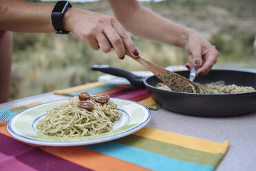 Close up of woman's hands preparing pasta with pesto during a trip. - CAVF80073