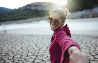 Smiling woman holding her hand for her boyfriend looking at the camera - CAVF80077