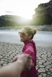 Smiling woman holding her hand for her boyfriend looking at the camera - CAVF80078