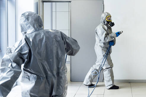 Reinigungspersonal desinfiziert das Krankenhaus gegen Infektionskrankheiten und trägt Schutzkleidung - JCMF00597
