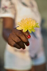 Gelbe Blume in der Hand einer Frau, Nahaufnahme - VEGF01963