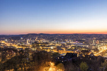 Germany, Baden-Wurttemberg, Stuttgart, Clear sky over illuminated city at dusk - WDF05971