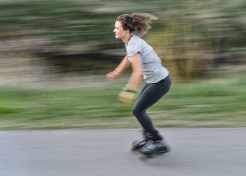 Blurred motion of woman inline skating on road - STSF02505