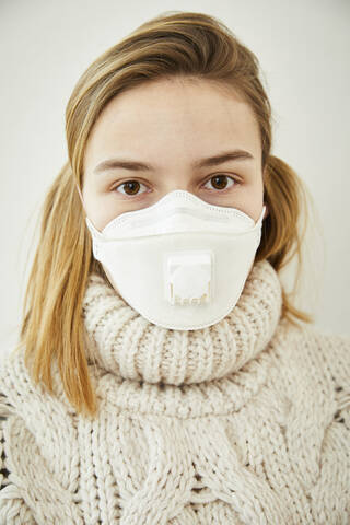 Portrait of blond woman wearing FFP2 mask at home stock photo