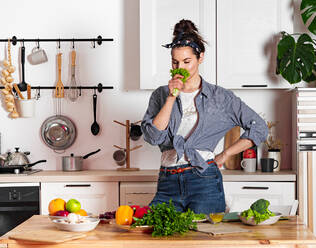 Young and beautiful housewife woman cooking in a white kitchen - CAVF80147