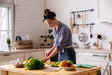 Junge und schöne Hausfrau Frau Kochen in einer weißen Küche - CAVF80159