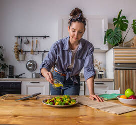 Young and beautiful housewife woman cooking in a white kitchen - CAVF80161